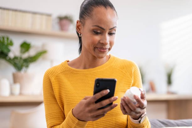 A woman checking her phone in a pharmacy. Her expression is neutral or thoughtful but she is not ashamed.