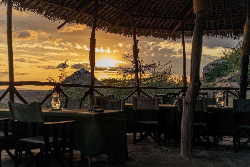 dinner set up in the wild with a sunset in the background and the view of a mountain