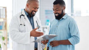 An African man sits calmly in a clinic, engaged in a relaxed consultation about vasectomy with a doctor