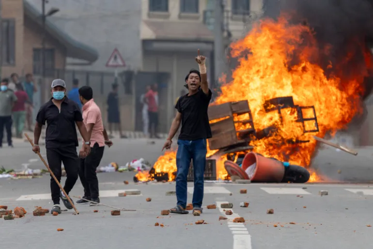 A Nepal protester in front a burning politician's house