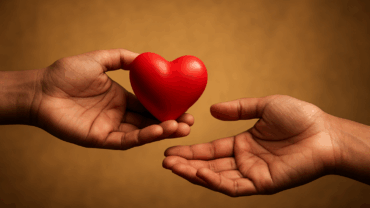 Stylized photo of two hands passing a glowing red heart, symbolizing donation and life.